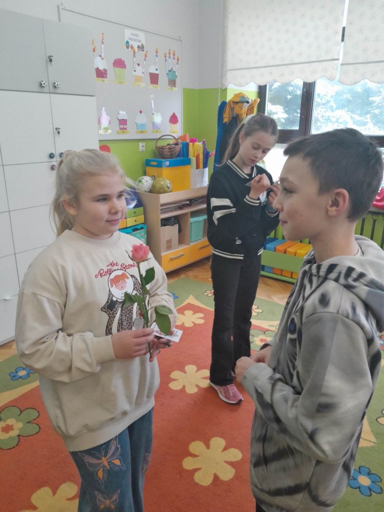 Chłopcy składają życzenia i podają dziewczynkom róże