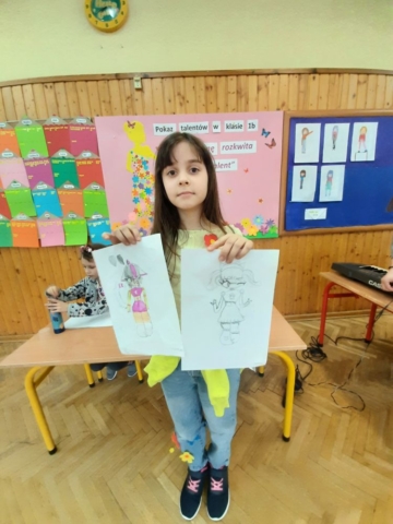 dziewczynka prezentuje swoje rysunki