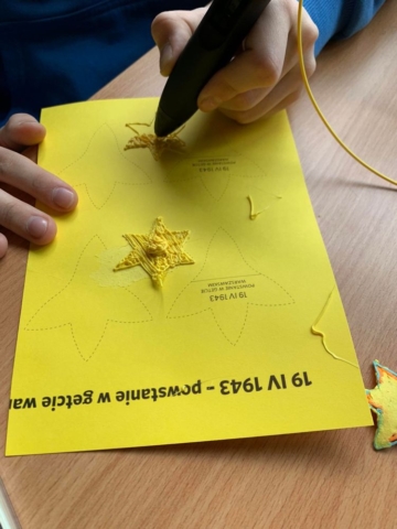 Uczennica tworzy żonkil przy pomocy długopisu 3D