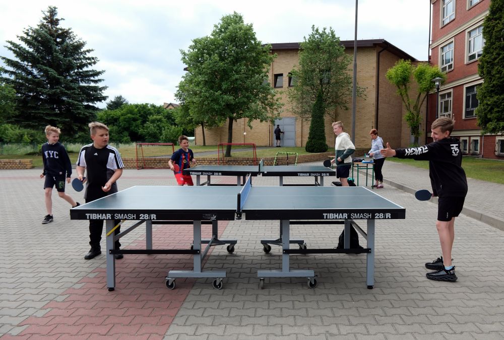 Chłopcy grają w tenisa stołowego na podwórku szkolnym