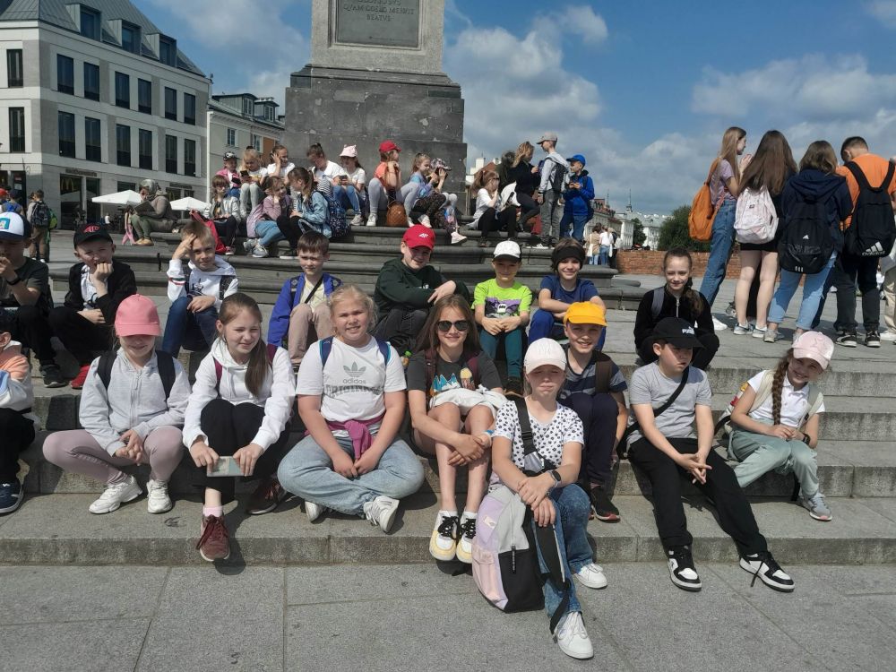 Dzieci siedzą pod Kolumną Zygmunta III Wazy
