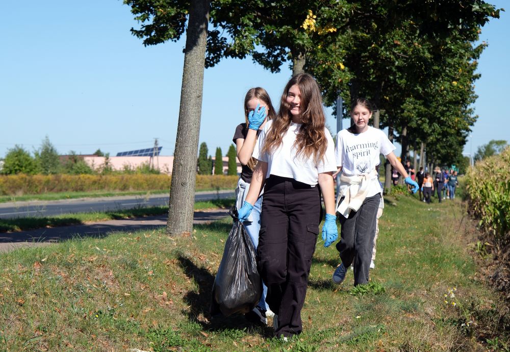 Uczniowie zbierają śmieci wzdłuż drogi