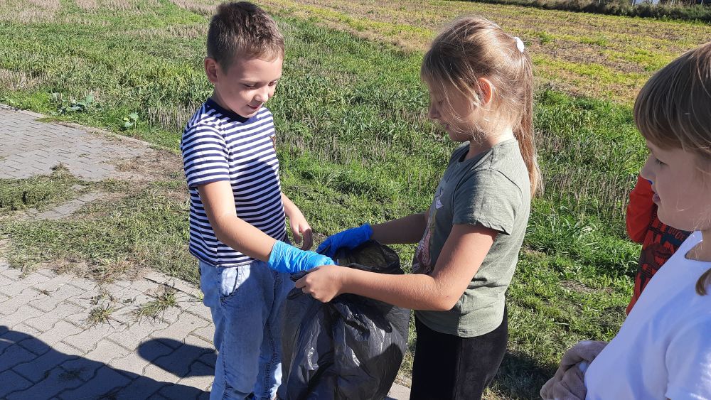 uczeń wrzuca znalezione śmieci do worka