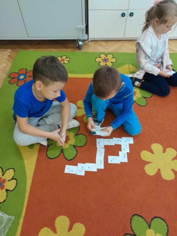 dzieci układają domino z cyframi oraz kolorami