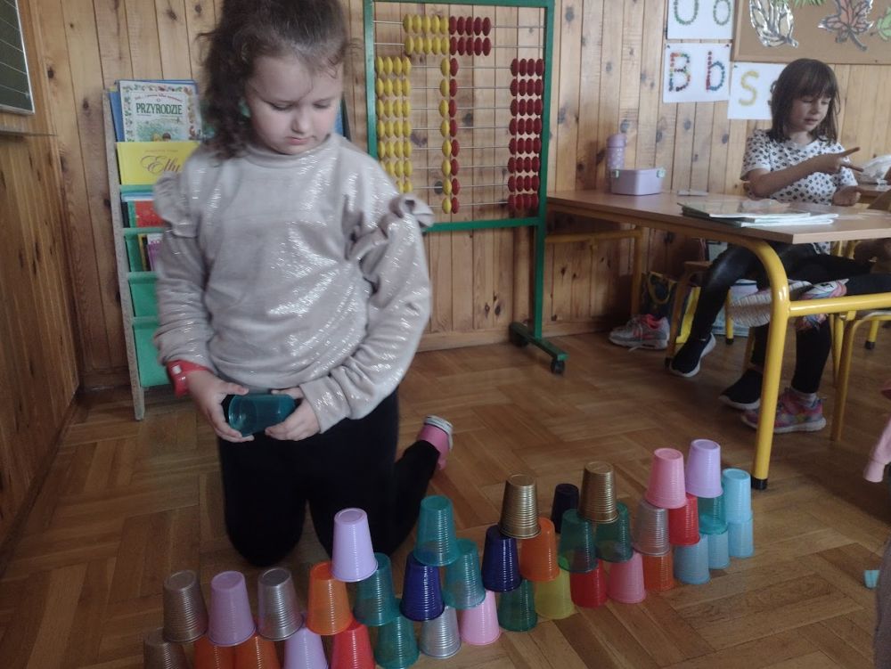 Dziewczynka buduje wieżę z kubeczków
