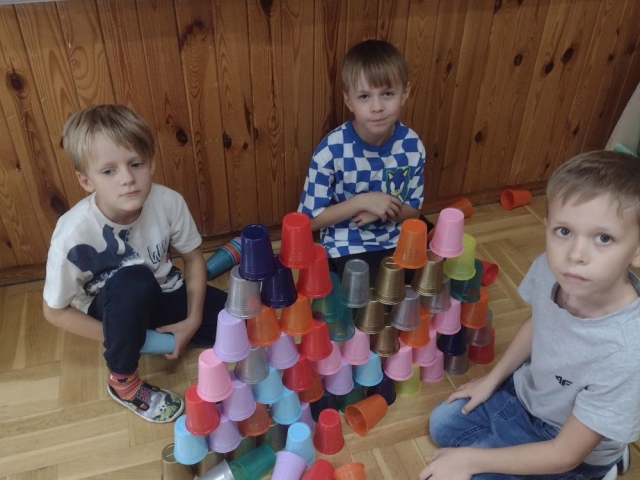 Chłopcy budują wieżę z kubeczków.