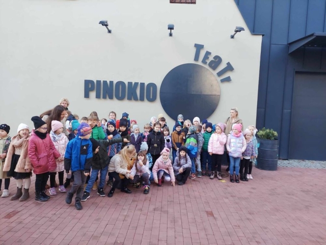 Grupa dzieci przed teatrem Pinokio w Łodzi. Na ścianie teatru widnieje napis Teatr Pinokio