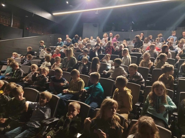 Uczniowie siedzący na krzesłach na widowni teatru Pinokio w Łodzi w oczekiwaniu na spektakl