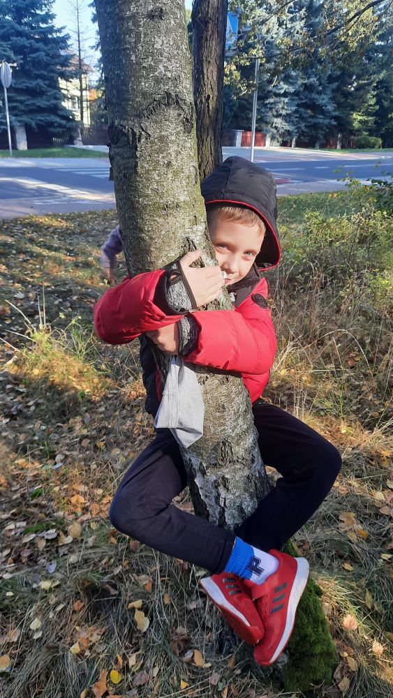 chłopiec przytula się do drzewa