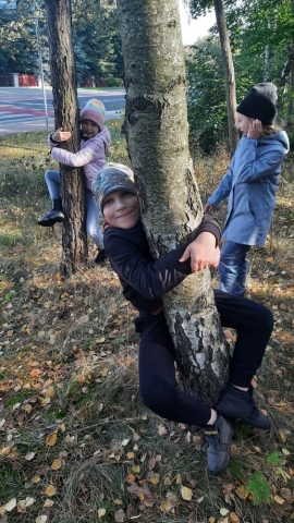 dzieci przytulają się do drzew