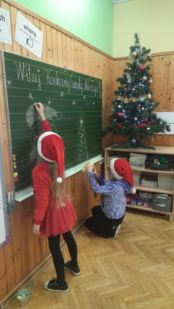 dzieci ozdabiają tablicę mikołajkowo powitanie dla Świętego Mikołaja