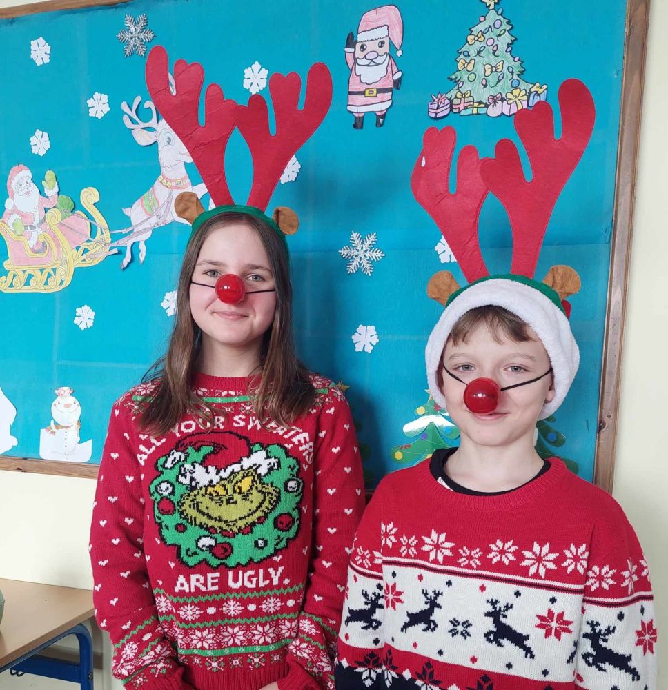Uczniowie w świątecznych swetrach, reniferowych rogach i z czerwonymi nosami